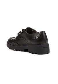 Scarpa brogue in pelle nera con dettagli perforati, design con lacci e suola in gomma nera robusta. Presenta il marchio "GEOX" sul tallone.