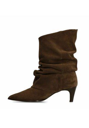 Bruine suède slouchy-laars tot halverwege de kuit met een puntige neus en een lage, gebogen hak, vanaf de zijkant getoond op een witte achtergrond.