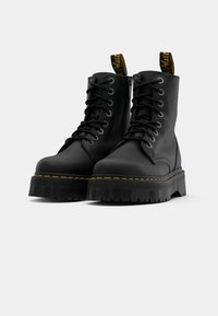 Black leather ankle boots with round toe, thick rubber sole, yellow stitching detail, and pull tabs for easy wear.