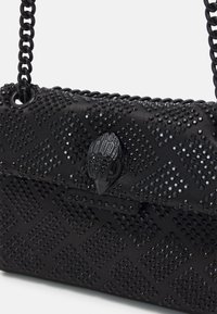 Sac à main noir avec un motif texturé, orné de clous noirs brillants. Dispose d'un fermoir décoratif et d'une bandoulière en chaîne.