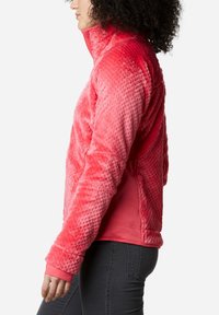 Pullover in pile in gradiente di rosa con colletto alto, superficie texturizzata e polsini aderenti. Interno liscio e dettaglio della tasca laterale.