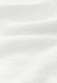 White fabric with a smooth texture, featuring soft folds and subtle variations in shade, indicating a lightweight and breathable material.