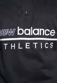 Černá mikina na zip s bílým vyšitým nápisem "new balance" a "ATHLETICS" a bílým vodorovným pruhem přes hruď.