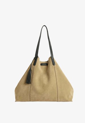 Sac fourre-tout en daim beige avec de longues poignées en cuir noir et un pompon, arborant une petite étiquette noire à l'avant.