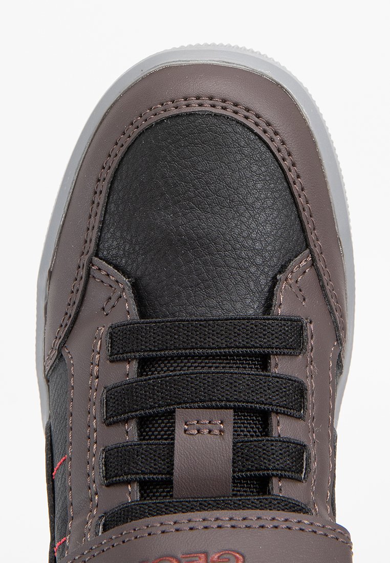 Baskets brun et noir avec une tige synthétique lisse, semelle en caoutchouc, système de laçage et détails de couture contrastés. Embout texturé.