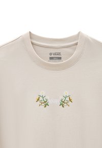 Beige Baumwoll-T-Shirt mit floralem Stickerei in Grün, Weiß und Gelb sowie zentriertem "VANS"-Logo. Rundhalsausschnitt und kurze Ärmel.