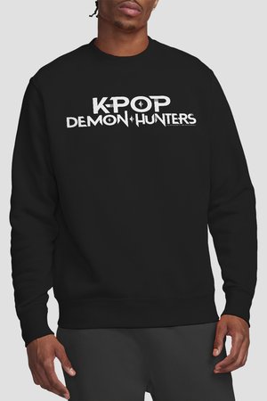 Mann trägt schwarzen Pullover mit weißem Text "KPOP DEMON HUNTERS" vorne, vor einfachem hellgrauem Hintergrund.