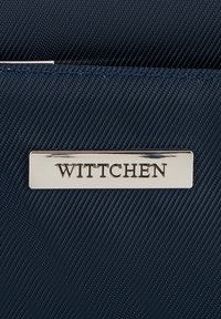 Navy textuur materiaal zakje met een zilveren rechthoekig plaatje waarop "WITTCHEN" is geperst, met fijne stiksels.