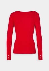 Rotes, geripptes Langarmshirt mit weitem Ausschnitt und Knopfdetails an den Bündchen. Der Stoff wirkt glatt und eng anliegend.