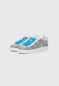 Basket blanche avec un motif abstrait noir, lacets bleus et semelle blanche. Présente un design basse et un bout arrondi.