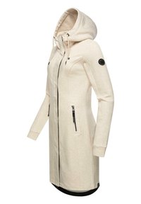Hooded lång jacka i ljusbeige, gjord av mjukt tyg. Har svarta blixtlås, sidofickor och en rund logotyp-patch på ärmen.