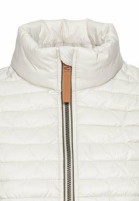 Gepolsterte weiße Weste mit hohem Kragen, Frontreißverschluss und kontrastierendem braunem Reißverschluss-Zipper. Verfügt über gesteppte Texturdetails überall.
