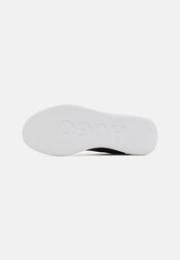 Black footwear with a textured surface, featuring a thick, white rubber sole embossed with "HUGO." The outsole has a smooth, contoured shape.