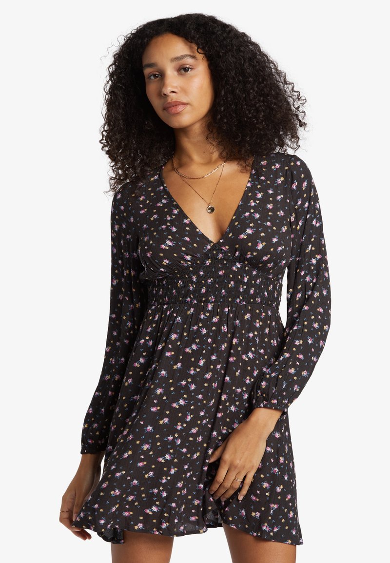 Black dress with long sleeves, a V-neck, and smocked waist. Features small floral patterns in pink and blue. Soft, lightweight fabric.