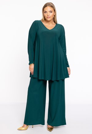 Haut long à manches en teal avec un col en V et une coupe fluide, associé à un pantalon large. Comprend un tissu doux et des talons aiguilles dorés.