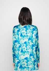 Top a maniche lunghe in tessuto leggero con un motivo tie-dye blu e teal a spirale, vestibilità rilassata e orlo arrotondato.