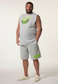 Canottiera grigia senza maniche con grafica "SUNSHINE MIAMI BEACH"; pantaloni corti grigi abbinati con "MIAMI BEACH" in verde brillante. Indossato con sneaker bianche.