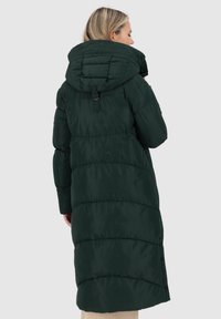 Cappotto puffer lungo verde con un grande cappuccio regolabile, pannelli a coste e chiusure laterali a bottone. Realizzato in un materiale liscio e imbottito.