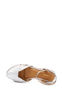 Sandal con tacco argento caratterizzato da un design incrociato, tomaia in pelle, punta aperta e cinturino alla caviglia. Finitura testurizzata con suola liscia.