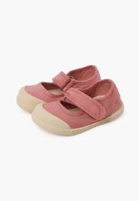 Zapatillas de lona rosas con punta redondeada, una correa de Velcro sobre el empeine y una suela de goma beige texturizada.