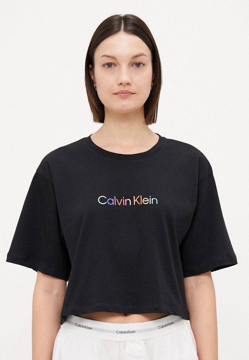 Svart kortärmad t-shirt gjord av mjukt tyg med en flerfärgad "Calvin Klein"-logotyp i en modern stil. Korta ärmar och rund halsringning.