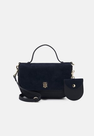 Navy suede handbag with a textured bottom, gold hardware, and a detachable round pouch. Features a top handle and crossbody strap.