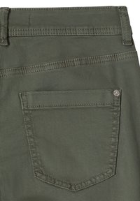 Poche arrière d'un jean en denim vert olive avec double surpiqûre et un petit rivet métallique dans le coin supérieur.