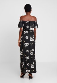 Černé maxi šaty s květinovým potiskem, s odkrytými rameny, krátkými rukávy, fitted pasem a splývající sukní. Mají lehkou látku a délku po kotníky.