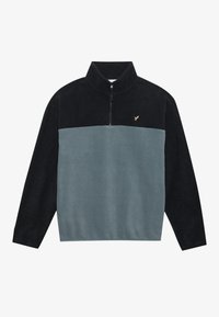 Sudadera de forro polar con cuello alto, con cierre de cremallera. Colores: azul marino oscuro y verde claro. Logo dorado en el pecho, textura suave.