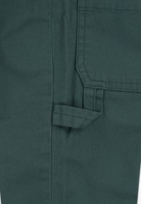 Dunkelgrüner Stoff mit geradem Design, seitlicher Tasche und einem kleinen Schlaufendetail am Saum. Glatte Textur und gleichmäßige Nähte.