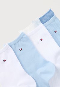 Τέσσερα ζευγάρια χαμηλά καλτσάκια σε λευκό και ανοιχτό γαλάζιο, το καθένα με ένα μικρό ορθογώνιο λογότυπο σε κόκκινο, λευκό και ναυτικό μπλε κοντά στη μανσέτα.