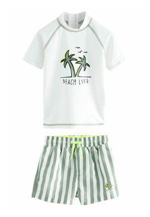 T-shirt de bain à manches courtes blanc avec le texte "BEACH LIFE" et un graphisme de palmier. Un short de bain rayé vert et blanc avec une taille élastique et un cordon de serrage.
