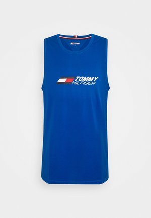 Haut de sport sans manches bleu avec logo Tommy Hilfiger et motif de drapeau rouge, blanc et noir sur la poitrine.