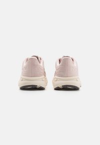 Zapatillas de correr de ante y malla rosa con una suela acolchada, que cuentan con un talón texturizado y una suela exterior en contraste de color crema. Branding minimalista visible.