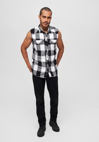 Fekete-fehér kockás ujjatlan ing, két mellzsebbel, fekete nadrággal és fekete csizmával párosítva. Egyszerű, hétköznapi dizájn.