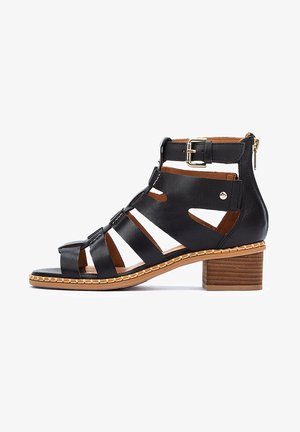 Black leather open-toe sandal with side cutouts, ankle strap and buckle, mid-height wooden block heel, and contrasting tan stitching.