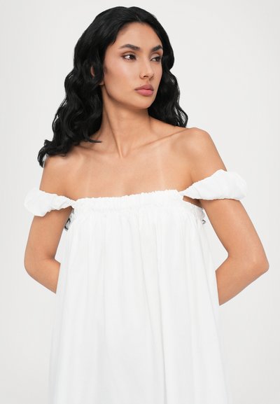 Rochie albă cu umeri goi, cu decolteu elastic și mâneci bulbuc, confecționată dintr-un material ușor; textură fină, design fluid.