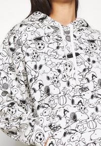 Felpa bianca con cappuccio caratterizzata da un motivo di cartoni animati di cani e attrezzature sportive in contorni neri, con cappuccio regolabile e maniche lunghe.