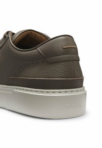 Tacco di sneaker in pelle marrone con texture, colletto imbottito, suola spessa bianca e logo "BOSS" in rilievo sul lato della suola.