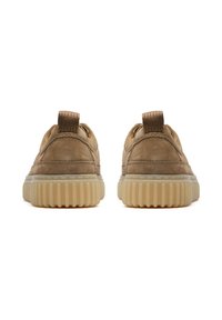 Un paio di sneakers in suede marrone chiaro con suole in gomma traslucida spessa e rigata, viste da dietro su uno sfondo bianco.