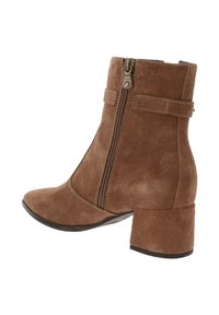Stivaletto in suede marrone con punta curva, zip laterale e tacco a blocco. Presenta una texture liscia e dettagli di cucitura minimi.