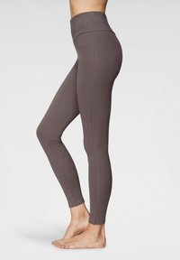 Leggings a vita alta, aderenti, realizzati in un morbido tessuto texturizzato marrone. Presentano un'ampia vita e un design senza cuciture lungo le gambe.