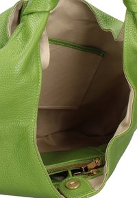 Sac à main en cuir vert avec une texture douce et une poignée nouée, doté d'une doublure intérieure beige et d'une poche zippée.