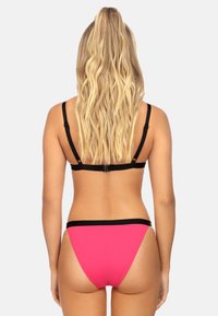 Różowy zestaw bikini z czarnym wzorem na ramiączkach. Góra ma regulowane ramiączka, a dół charakteryzuje się wycięciem w stylu high cut i czarnym pasem w talii.