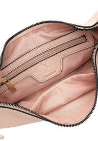 Interno di una borsa in pelle rosa con una tasca con cerniera, rivestimento in tessuto liscio, cerniera nera e un accento in pelle con logo.