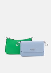 Due piccole borse Kate Spade New York: una verde con zip, l'altra azzurro chiaro con patta e chiusure in argento, su sfondo bianco.