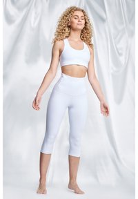 Witte sportieve crop top en aansluitende capri leggings van glad, rekbaar materiaal. Minimalistisch ontwerp zonder zichtbare patronen of accenten.