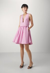 Robe sans manches rose avec un décolleté en V profond, taille cintrée et jupe évasée. Équipée de poches latérales et d'une texture lisse.