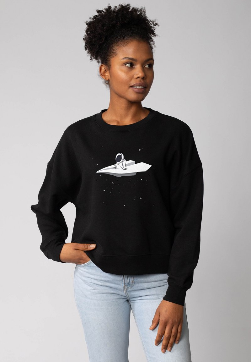 Zwarte sweatshirt met een ontspannen pasvorm, voorzien van een witte astronautafbeelding op een ruimteschipontwerp en kleine sterren, gemaakt van zachte stof.