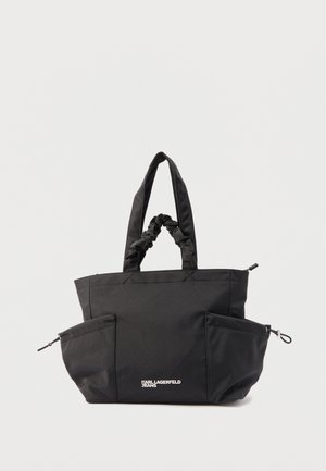 Črna torba tote z dvema oblazinjenima ročajema, dvema stranskima žepoma z zadrgo in belim logotipom "Karl Lagerfeld Jeans" na sredini sprednje strani.